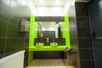 Modern public toilet sinks and mirror with green and black tiles