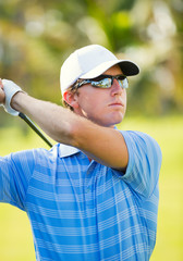 Young man swinging golf club