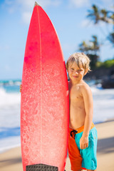 happy young boy at the beach with surfboard