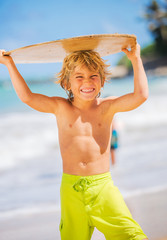 Happy Young boy having fun at the beach on vacation, with skimbo