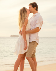 Happy romantic couple on the beach at sunset embracing each othe