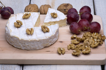 cheese, walnuts, grapes, on a chopping board on an old table