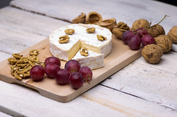 cheese, walnuts, grapes, on a chopping board on an old table
