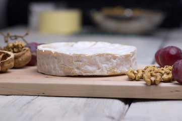 cheese, walnuts, grapes, on a chopping board on an old table