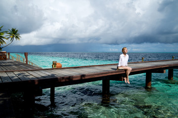Girl is relaxing on a pier in the ocean