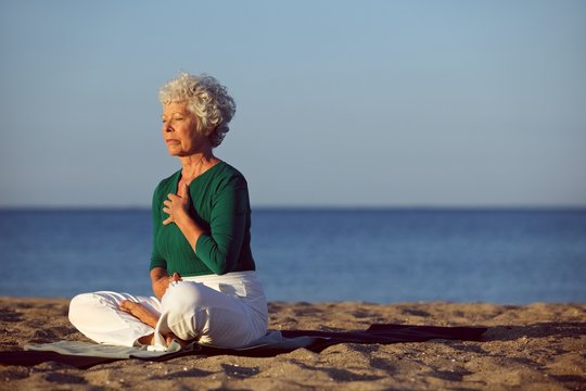 Senior woman in meditation by ocean
