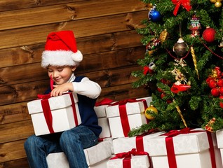 Obraz na płótnie Canvas Little boy with gift box under christmas tree