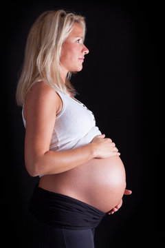 Pregnant woman touching her belly with hands. Isolated over a bl