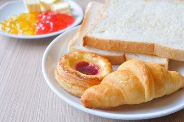 Fototapeta na wymiar Various breads and Croissants with Jams on breakfast table.