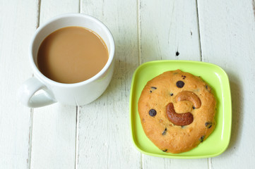 Almond-cookie on green plate with coffee on wood table.