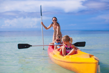 Two little girl and beautiful mother kayaking at tropical warm