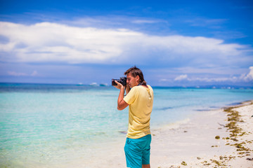 Young man photographing with a camera in his hands on a tropical