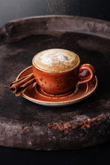 Cup of Cappuccino Coffee with cinnamon on dark background