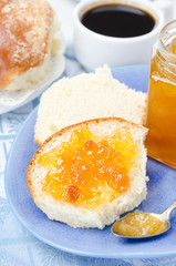 Sweet bun with apricot jam and cup of coffee for breakfast