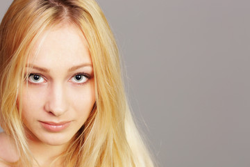 Fototapeta premium closeup portrait of a young blonde girl on gray background