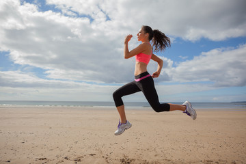 Fototapeta na wymiar Full length of healthy woman jogging on beach
