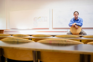 Male teacher sitting on chair in lecture hall