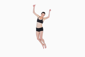Fototapeta na wymiar Sporty young woman jumping over white background