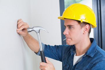 Handyman hammering nail in wall