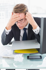 Worried businessman with documents at office desk