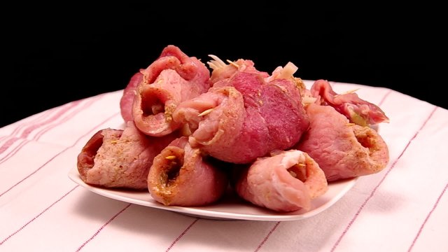 Raw stuffed pork slices are rotating on the table.