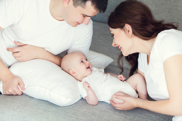 mother and father playing with their cute baby on at home