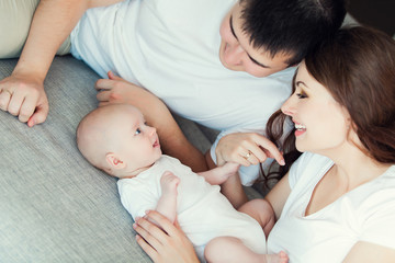 mother and father playing with their cute baby on at home
