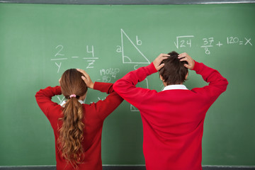 Confused Schoolchildren Standing Against Board