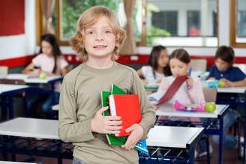 Schoolboy Holding Books With Classmates In Background