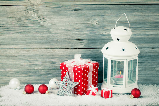 Burning lantern in the snow with christmas decoration, on wood b