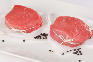Raw beef steaks with pepper on white background
