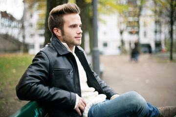junger Mann sitzt auf einer Parkbank