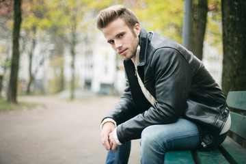 Obraz premium junger Mann sitzt auf einer Parkbank