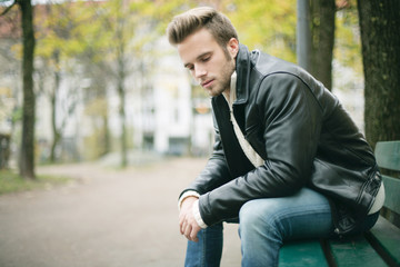 junger Mann sitzt auf einer Parkbank