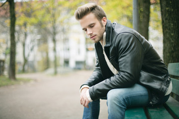 Obraz premium junger Mann sitzt auf einer Parkbank