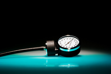 Sphygmomanometer on blue, reflective table and black background