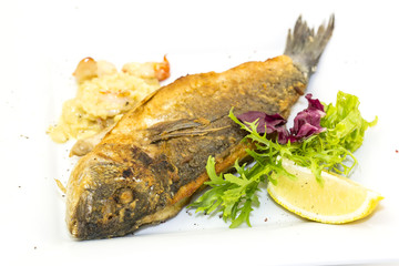 Fried fish dorado with vegetables and lemon