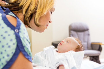 Fototapeta na wymiar Woman Looking At Cute Newborn Babygirl In Hospital