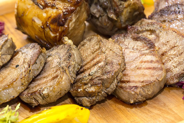 loin and steak cooked on a grill with vegetables