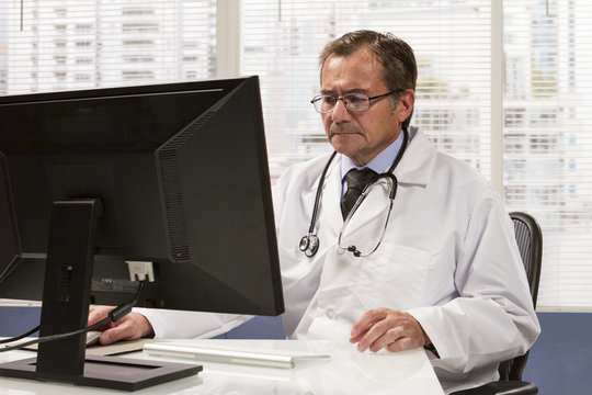 Doctor at desk using computer, horizontal