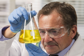 Lab scientist examining beaker, horizontal