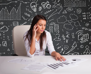 Businesswoman sitting at desk with business scheme and icons