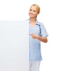 smiling female doctor or nurse with blank board