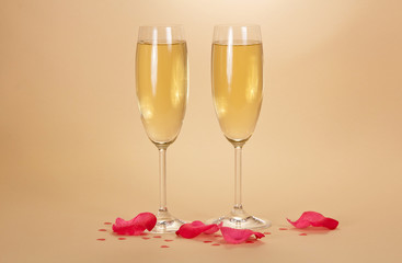 Two wine glasses of champagne and rose petals