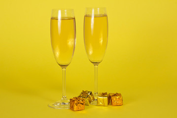 Two wine glasses with champagne and small bright gift boxes