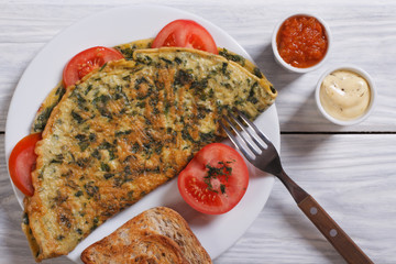 An omelet with spinach and sauce close-up view from above
