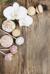 Top view of cake pops, muffins, cupcakes and macarons on wood