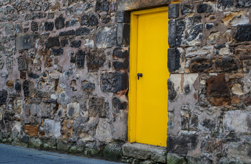 Yellow door on an old stone wall