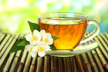 Cup of tea with jasmine, on bamboo mat, close-up