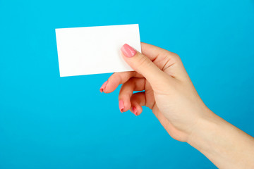 Female hand holding business card, on color background